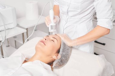 Güzellik uzmanı, gençleşen kadın yüzü için kriyoterapi yapıyor güzellik salonlarında yaşlanma karşıtı kozmetik prosedürler uyguluyor. Kozmetik uzmanı, cilt gençleştirme ve düzleştirme için kriyo terapi yapıyor.