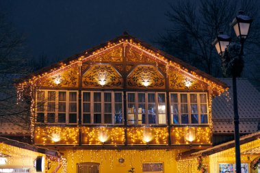 Noel dekoratif sarı çelenk ışıkları ve açık hava dekorasyonu olan zencefilli kurabiyeli evin ikinci katı. Güzelim zencefilli ev tarzı akşam çiçeklerinde