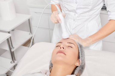 Güzellik uzmanı, güzellik salonundaki gençleştirme kadın yüzü için RF kaldırma, yaşlanma karşıtı kozmetik işlemleri yapıyor. Kozmetik uzmanı, kadın yüz derisinde artan kolajen için radyo frekansı tedavisi yapıyor.