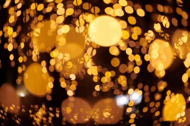 Sarı ışıklar Noel tatili çelenkleri, bulanık arka plan, soyut açık hava ışıkları ve sigara. Parlak sarı Bokeh ışıkları, güzel, karanlık gece arkaplanı.