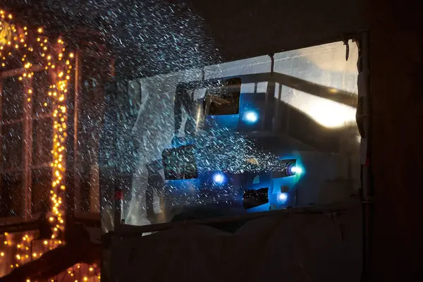 Movie projector lights at outdoor winter film show, blurred snow falls through colorful rays of film projector, outdoor street entertainment. Outdoor evening city lights installation