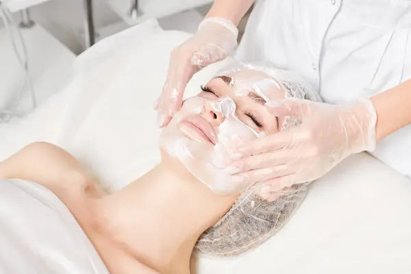 Cosmetologo Massaggia Maschera Alla Panna Pelle Faccia Donna Ringiovanimento Procedura Immagine Stock