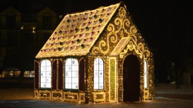 Küçük peri masalı evi pırıl pırıl çelenk ışıkları ve parıltılı desenlerle dekore edilmiş, gece kenti Noel süslemesi mutlu yeni yıl havası için, evin dış tarafında yanıp sönen sarı ışıklar.