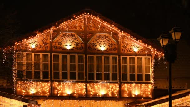 童话般的房子装饰着闪闪发光的花环和闪闪发光的图案 房子的外墙装饰着圣诞的气氛 房子的外墙闪烁着黄色的灯光 — 图库视频影像