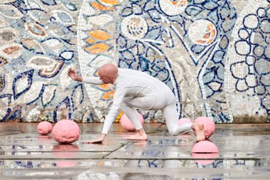 Beyaz fütüristik takım elbiseli, soyut mozaik Sovyet arka planındaki pembe küreler arasında plastik ve esnek hareketlerle genç balerin kızın açık hava dansı kendini ifade etmeyi sembolize eder.