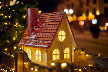 Gece vakti şehir sokağında sıcak camları olan Noel Masalı Evi, Yeni Yıl arifesinde festival şehir sokağının önünden geçen herkese sıcaklık ve neşe saçan kış mevsiminin ruhunu simgeler.