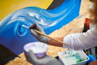 Kadın sanatçı eli, boya fırçasıyla fırça darbelerini tuvale uygular sergi için resim yaratır, kadın el ressamı yaratıcı sürecini kapatır