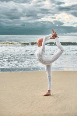 Beyaz fütüristik takım elbiseli genç tüysüz balerin kumlu sahilde dans ediyor. Kel, genç ve güzel bir kızla mecazi gerçeküstü bir performans sergiliyor. Kendine güveni ve eşsiz bir güzelliği var.