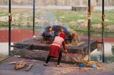 Pashupatinath Tapınağı 'nın personel çalışanı. Cenaze töreni için odun yığınına nezaret ediyorlar. Ölümü ve yaşamı sembolize eden eski bir gelenek.