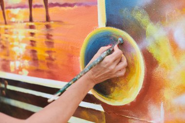 Kadın ressam el, resim çizer. Resim fırçasıyla sergi için, kadın el sanatları ressamının küçük dokunuşlarla muhteşem bir resim çizdiği yakın plan.