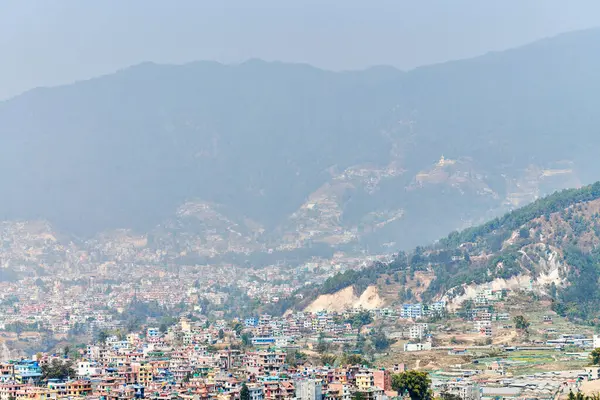 Nepal 'in Katmandu başkentinin dağdan şehir sisi boyunca manzarası alçak binalar, şehir manzarası dağ havasında ruhani bir atmosfer yaratıyor, Kathmandu hava kirliliği