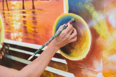 Kadın ressam el, resim çizer. Resim fırçasıyla sergi için, kadın el sanatları ressamının küçük dokunuşlarla muhteşem bir resim çizdiği yakın plan.