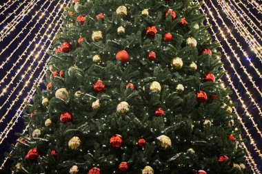 Yeni yıl ağacı süslenmiş kırmızı sarı Noel topları çelenk ışıkları, yakın görüş, mutlu Noel ve mutlu yeni yıl, bayram neşesi ve neşeli ruhun özü