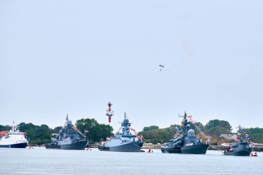 Hava kuvvetleri paraşütçüleri Rus bayrağını dalgalandırıyor kıyı şeridi boyunca savaş gemilerini geçit törenine sokuyor, Donanma Günü 'nde askeri gemilerin oluşumu, Rus deniz kuvvetlerinin deniz manzarası...