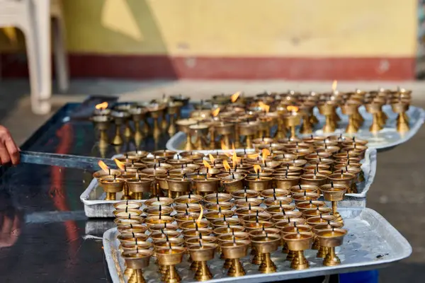 Nepalli tapınak personeli, fitil yandıktan sonra yenisi için mum yağı dökerek bronz mum tutucuları yeniden kullanacak, gönüllü olarak Kathmandu 'daki Boudhanath Stupa tapınağında çalışacak.