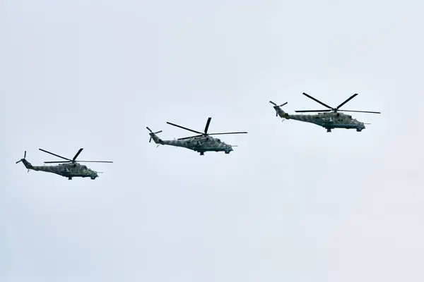 stock image Three Russian military helicopters armed with missiles flies in blue sky, airborne mission of gunships with targeting system performs an aerial maneuvers for military operation, russian aviation