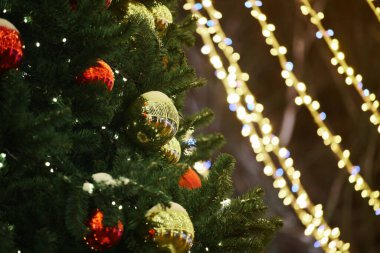 Yeni yıl ağacı süslenmiş Noel baloları, yanıp sönen sarı çelenk ışıklarıyla fotokopi alanı, mutlu noeller ve parıldayan süsleme ışıklarıyla mutlu noeller.