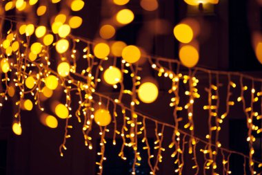 Yılbaşı için sarkık çelenklerin yanıp sönen ışıkları gece sokak süslemeleri, mutlu noeller ve çözülmüş parlayan ışıklarla mutlu yeni yıl havası.