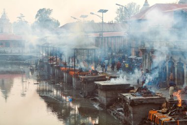 Katmandu, Nepal - 01.02.2023 - Pashupatinath Tapınağı kompleksinde yas yakma töreni, Pandra Shivalaya 'nın yakıldığı yerden manzara, yaşam ve ölümün döngüsel doğasını sembolize ediyor.