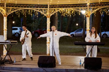 Svetlogorsk, Russia - 13.08.2023 - Local pop rock music band performs in gazebo of city public park, energetic outdoor performance of keyboardist, guitarist and vocalist in evening lights of park clipart