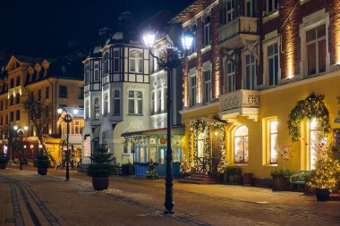 Zelenogradsk, Rusya - 09.01.2022 - Yeni Yıl dekorasyonları ve parıldayan çelenk gece lambalarıyla süslenmiş, caddeyi Noel harikalar diyarına çeviren Noel sıcaklığı ve bayram havası