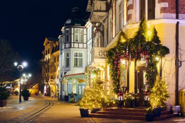 Zelenogradsk, Rusya - 09.01.2022 - Yeni Yıl dekorasyonları ve parıldayan çelenk gece lambalarıyla süslenmiş, caddeyi Noel harikalar diyarına çeviren Noel sıcaklığı ve bayram havası