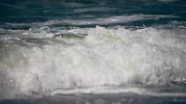 Güneşli bir günde kıyıya vuran yumuşak okyanus dalgaları, yakın görüş.