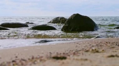 Huzurlu kıyı sahnesinde, kum gibi hafif dalgalarla benekli büyük kayalar sergileniyor. Sessizliği ve doğayla bağlantıyı çağrıştırıyor. Yansıma için mükemmel.