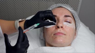 Profesyonel, klinik ortamda genç yetişkin kadın müşterilere kozmetik enjeksiyon yapar. Manzara güzellik ve cilt bakımını, sakinliği ve hassas atmosferi yansıtıyor.