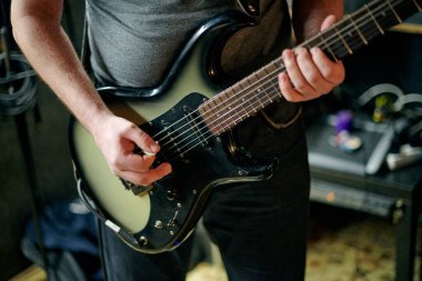 Müzik provasında elektro bas gitar çalan müzisyen, loş ayarlarda gitar tekniği pratik yapan, gitarist ellerini kapat
