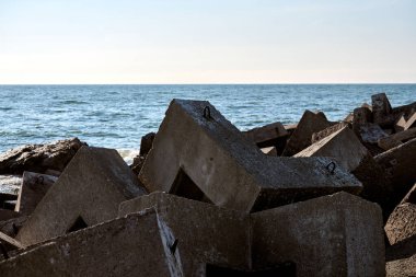 Büyük beton bloklar kıyı dalgaları oluşturarak okyanus dalgalarına karşı koruyucu bariyer oluşturur. Serin mavi gökyüzü deniz kenarının huzurlu atmosferini arttırır.