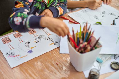 Çocuk ahşap yüzeyde renkli çizimler yapıyor. Odaklanan parlak kalemler. Doğal ışık arttırıcı yaratıcılığa sahip sıradan bir iç mekan