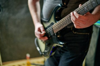 Müzik provasında elektro bas gitar çalan müzisyen, loş ayarlarda gitar tekniği pratik yapan, gitarist ellerini kapat