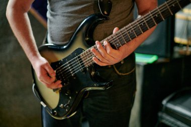 Müzik provasında elektro bas gitar çalan müzisyen, loş ayarlarda gitar tekniği pratik yapan, gitarist ellerini kapat