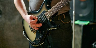 Müzik provasında elektro bas gitar çalan müzisyen, loş ayarlarda gitar tekniği pratik yapan, gitarist ellerini kapat