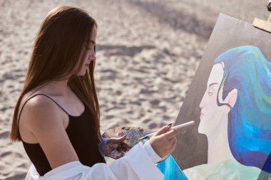 Young female artist paints on canvas at beach, evoking serenity and inspiration. Her artistic expression harmonizes with natural setting, underlining creativity and peace clipart