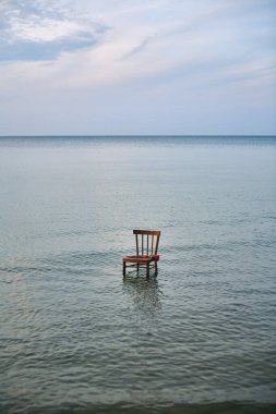 Tahta sandalye durgun, uçsuz bucaksız okyanusta duruyor, yalnızlığı ve düşünmeyi simgeliyor. Suyun ve gökyüzünün durgunluğu meditasyon havası yaratır. Huzur ve içgözlem duyguları uyandırır.
