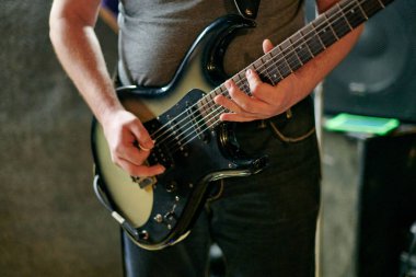 Müzik provasında elektro bas gitar çalan müzisyen, loş ayarlarda gitar tekniği pratik yapan, gitarist ellerini kapat