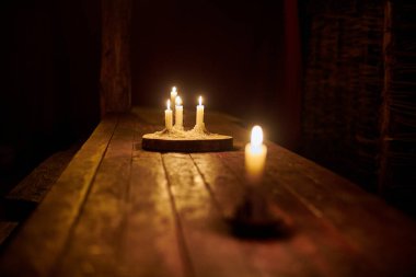 Ahşap tabanda dört mum, karanlık, rahat ve huzurlu atmosferde köy masasını aydınlatır. Eski bir meyhane masasında mum, eski bir meyhanenin çekiciliğini çağrıştırıyor, sakin bir ortam.