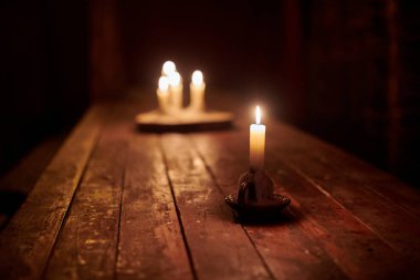 Ahşap tabanda dört mum, karanlık, rahat ve huzurlu atmosferde köy masasını aydınlatır. Eski bir meyhane masasında mum, eski bir meyhanenin çekiciliğini çağrıştırıyor, sakin bir ortam.