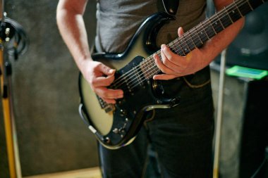 Müzik provasında elektro bas gitar çalan müzisyen, loş ayarlarda gitar tekniği pratik yapan, gitarist ellerini kapat