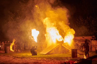 Kaliningrad, Rusya - 10.09.2022 - Gece gökyüzünde ışıl ışıl yanan ateş personeli silueti, bir açık hava yangın gösterisi sırasında enerji ve ateş manipülasyonu sanatını sergiliyor