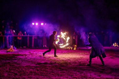 Kaliningrad, Rusya - 10.09.2022 - Muhteşem gece gösterisinde ateş topuyla dans eden sanatçı, gece gökyüzü altında ateşli hareketler, izleyiciler