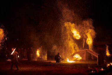 Kaliningrad, Rusya - 10.09.2022 - Gece gökyüzünde ışıl ışıl yanan ateş personeli silueti, bir açık hava yangın gösterisi sırasında enerji ve ateş manipülasyonu sanatını sergiliyor