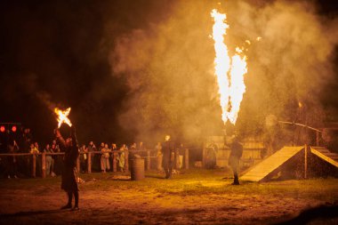 Kaliningrad, Rusya - 10.09.2022 - Çift alev fırlatıcı sanatçılar gece gökyüzüne muazzam alev akıntıları salıyor, ateş ustalığını ve ateş performansını temsil ediyor