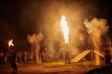 Kaliningrad, Rusya - 10.09.2022 - Çift alev fırlatıcı sanatçılar gece gökyüzüne muazzam alev akıntıları salıyor, ateş ustalığını ve ateş performansını temsil ediyor