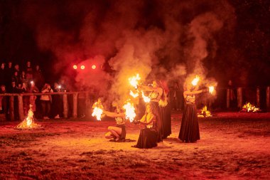 Kaliningrad, Rusya - 10.09.2022 - Muhteşem gece gösterisinde otantik bir elbiseyle dans eden ateş gösterisi sanatçıları, gece gökyüzü altında ateşli hareketler, izleyiciler
