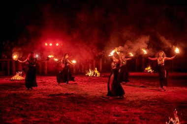 Kaliningrad, Rusya - 10.09.2022 - Muhteşem gece gösterisinde otantik bir elbiseyle dans eden ateş gösterisi sanatçıları, gece gökyüzü altında ateşli hareketler, izleyiciler