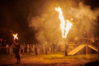 Kaliningrad, Rusya - 10.09.2022 - Çift alev fırlatıcı sanatçılar gece gökyüzüne muazzam alev akıntıları salıyor, ateş ustalığını ve ateş performansını temsil ediyor