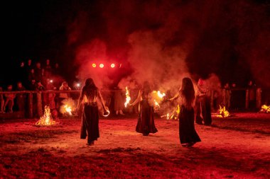 Kaliningrad, Rusya - 10.09.2022 - Muhteşem gece gösterisinde otantik bir elbiseyle dans eden ateş gösterisi sanatçıları, gece gökyüzü altında ateşli hareketler, izleyiciler